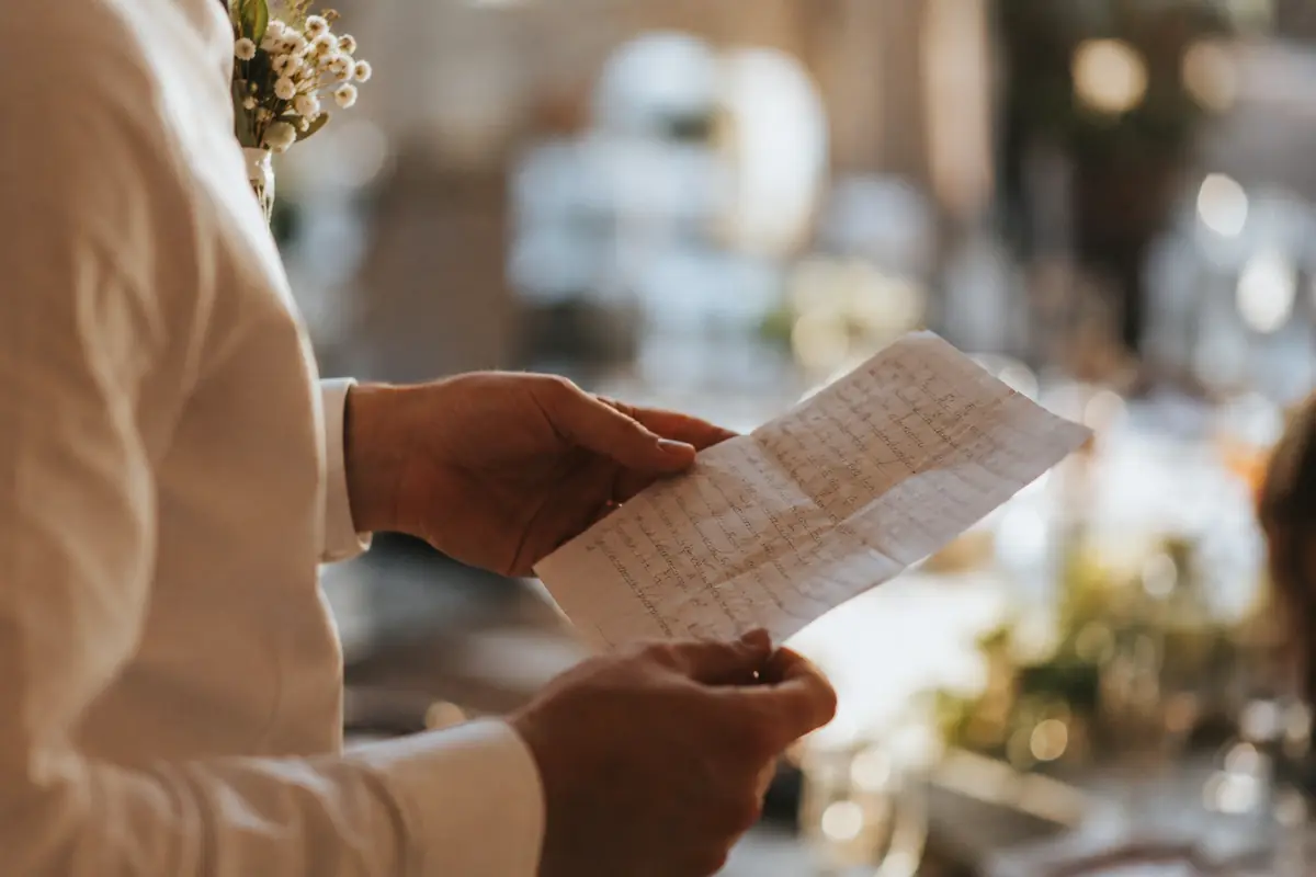 Des notes manuscrites pliées, tenues à deux mains pendant un mariage.